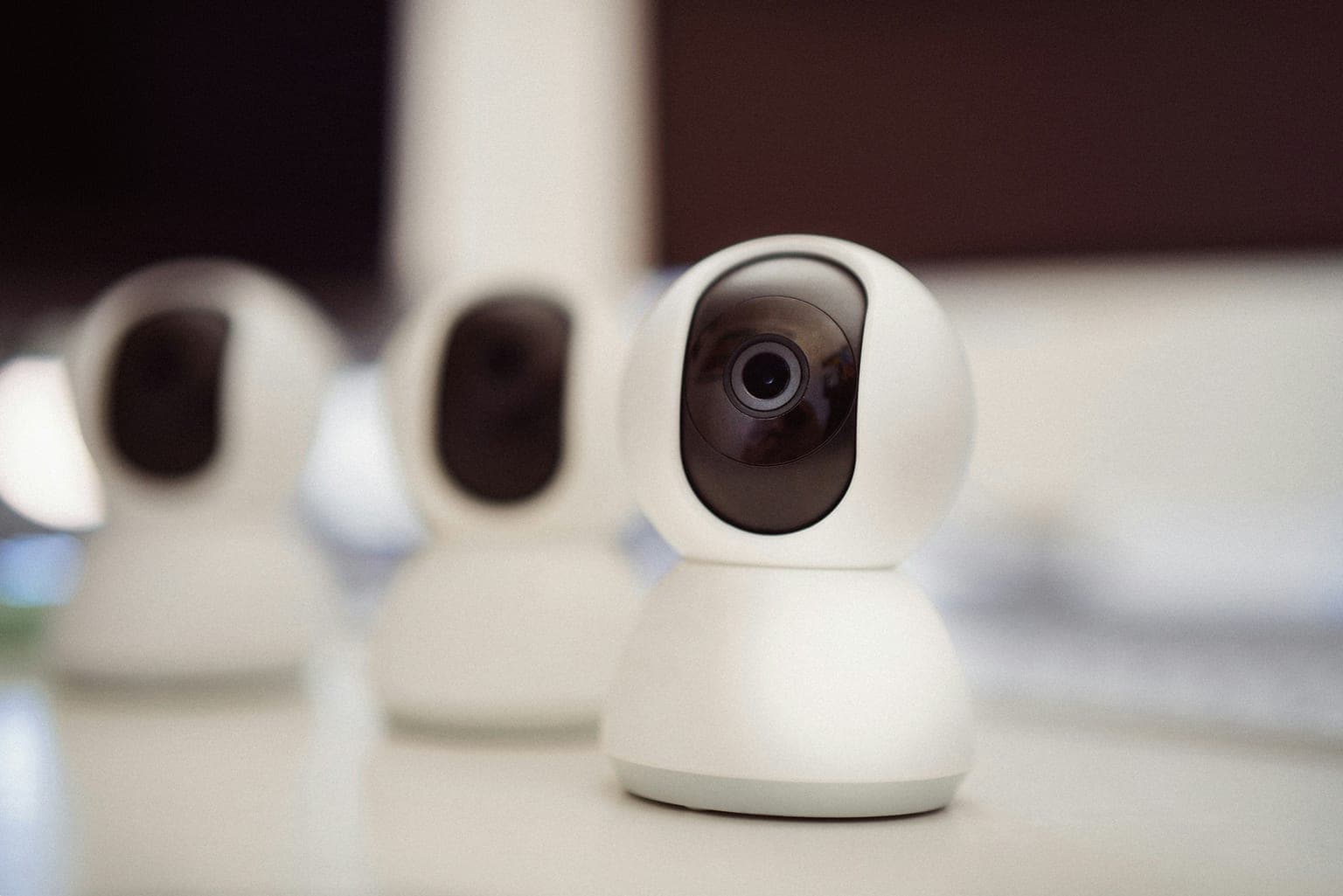 Row of white indoor security cameras on a desk, representing closed-loop baby monitor hardware