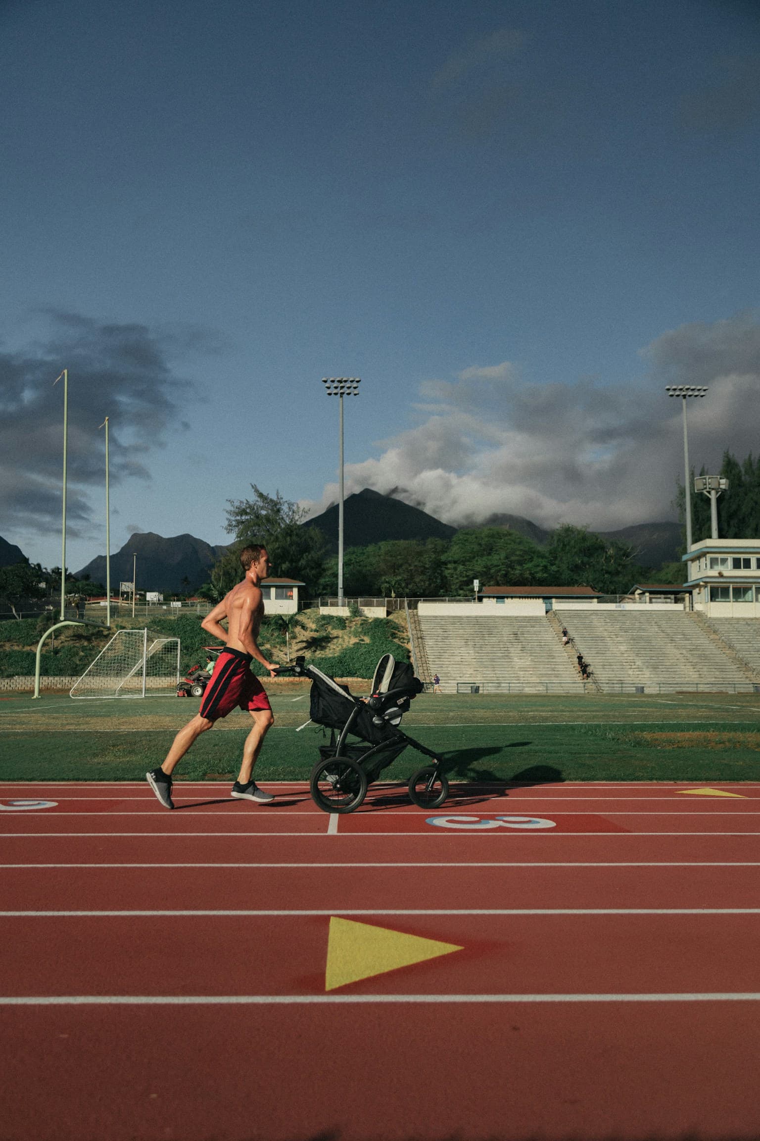 Man running while pushing a jogging stroller on a paved path outdoors